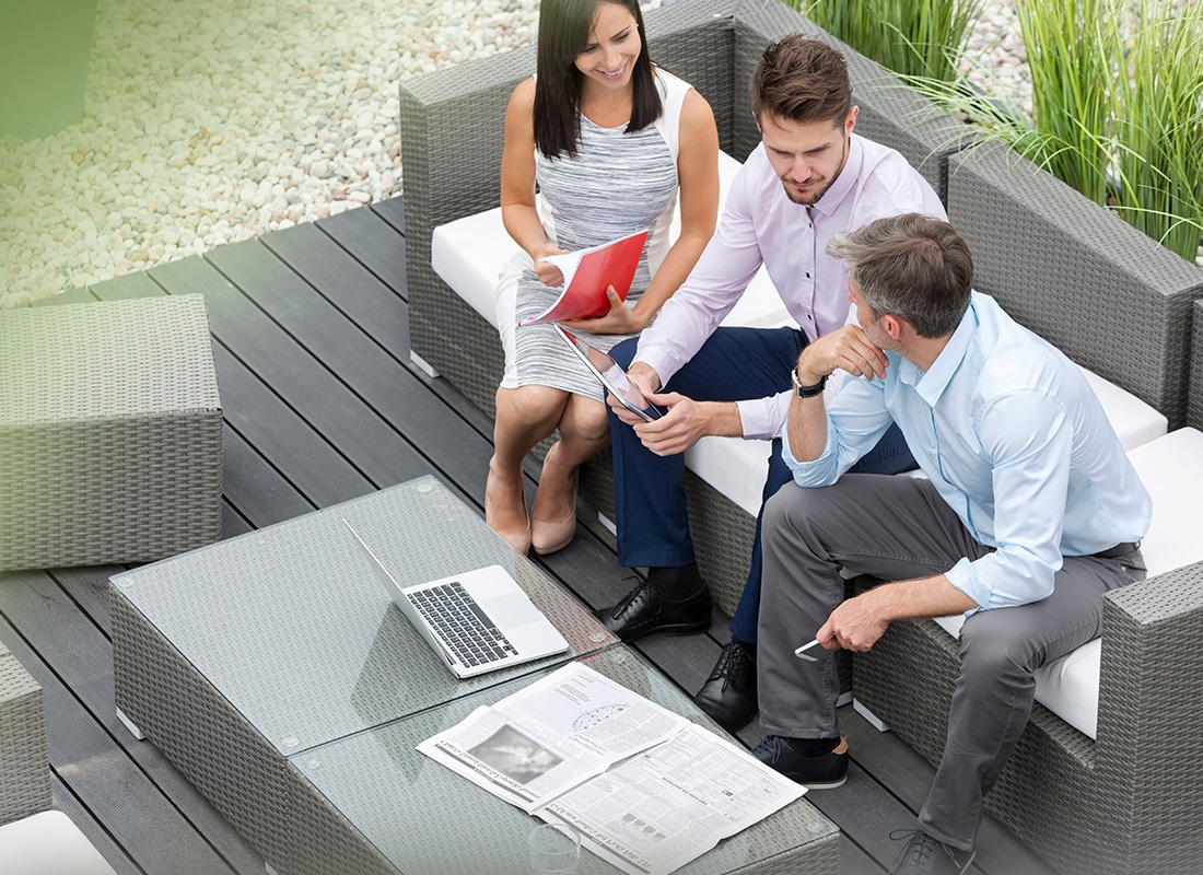 About Our Agency - Overhead View of Three Business Professionals Sitting Together at an Outdoor Patio Area
